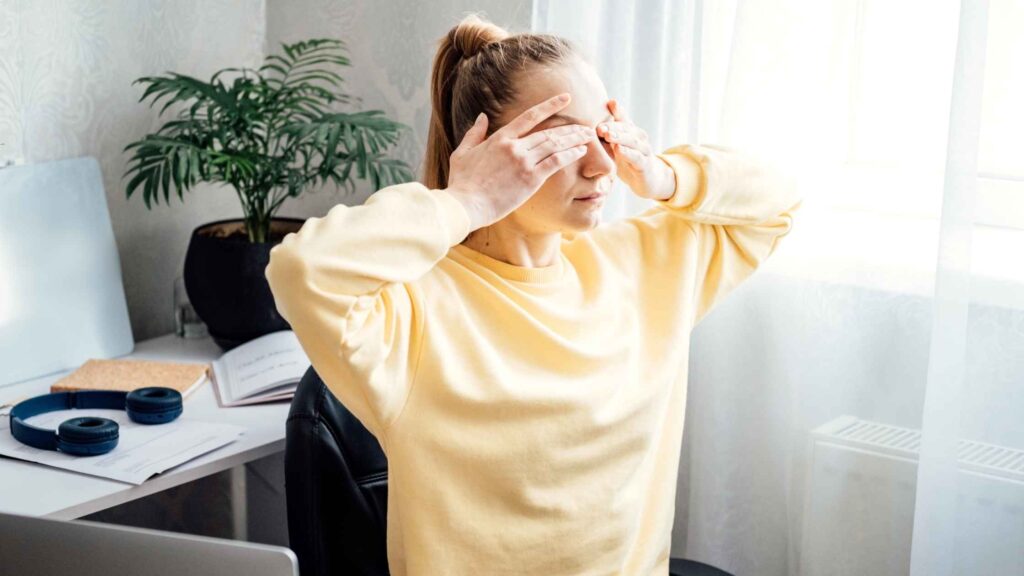 Femme en pull jaune en train de faire un palming comme exerice pour les yeux
