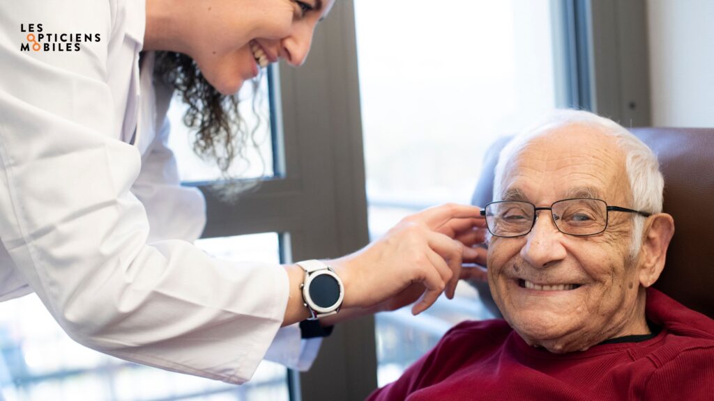 Photo d'un résident d'EHPAD sur la droite et d'une opticienne mobile sur la gauche en train d'ajuster les nouvelles lunettes du résident directement dans son fauteuil.